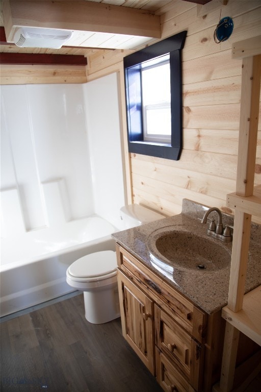 full bathroom with toilet, wood-type flooring, tub / shower combination, wood walls, and vanity