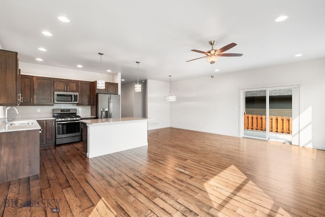 kitchen with decorative light fixtures, a kitchen island, ceiling fan, dark wood-type flooring, and appliances with stainless steel finishes