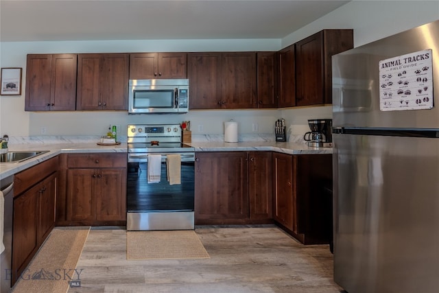 kitchen featuring stainless steel appliances, sink, and light hardwood / wood-style flooring