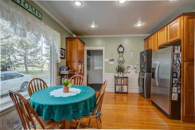 dining space with crown molding, stacked washer / dryer, and light wood-type flooring