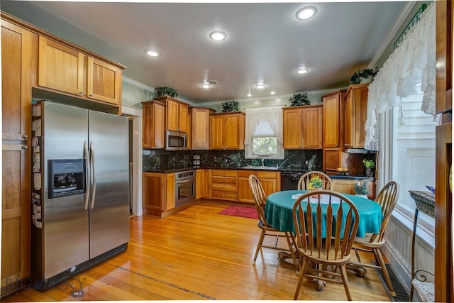 kitchen with tasteful backsplash, stainless steel appliances, ornamental molding, sink, and light wood-type flooring