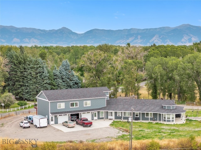 rear view of house with a mountain view, a garage, and a lawn