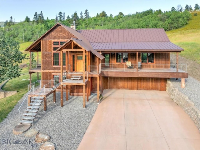 view of front of property featuring stairway, a chimney, a standing seam roof, and metal roof