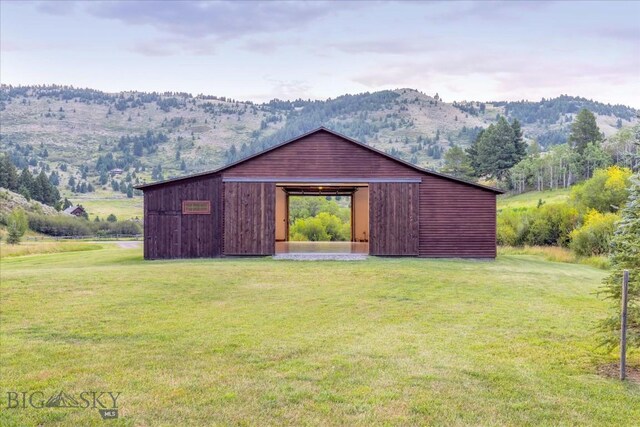 view of outdoor structure with a mountain view, a yard, and a rural view