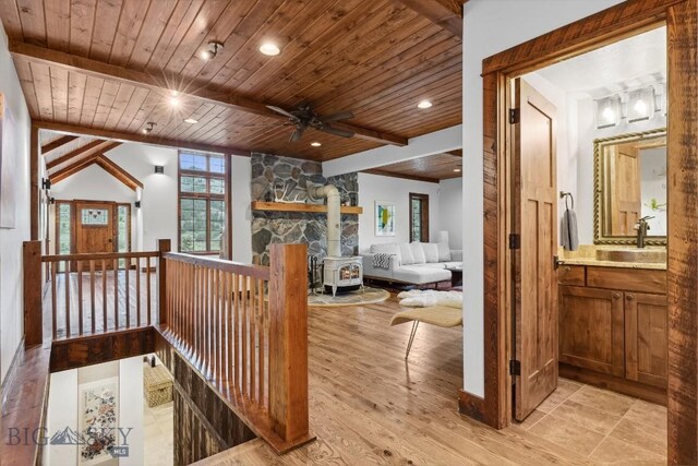 hallway featuring lofted ceiling with beams, light wood-type flooring, wood ceiling, and sink