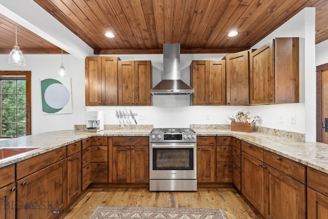 kitchen with pendant lighting, gas range, wall chimney exhaust hood, light wood-type flooring, and kitchen peninsula