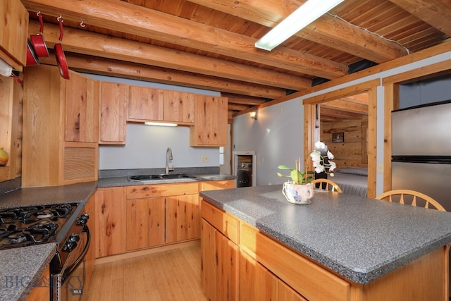 kitchen featuring black range with gas cooktop, sink, beamed ceiling, light hardwood / wood-style floors, and a kitchen island