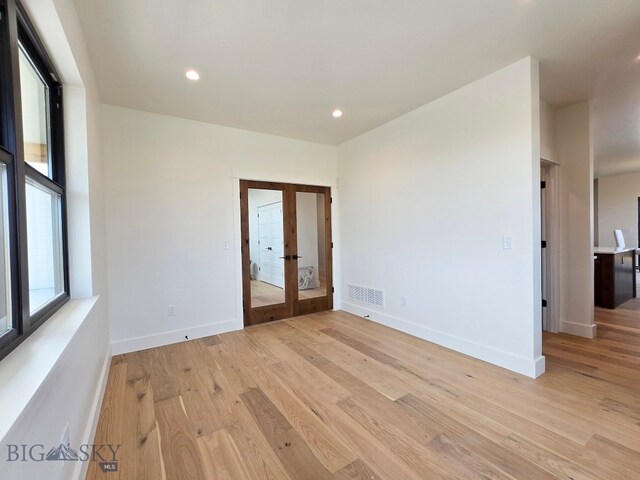 spare room with french doors and light hardwood / wood-style flooring