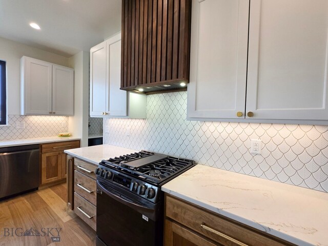 kitchen with dishwasher, light wood-type flooring, light stone counters, white cabinetry, and black range with gas stovetop