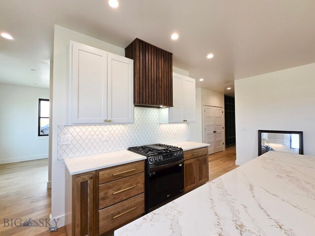 kitchen featuring black gas stove, light hardwood / wood-style flooring, and white cabinetry