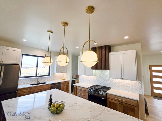 kitchen with appliances with stainless steel finishes, white cabinetry, sink, and pendant lighting