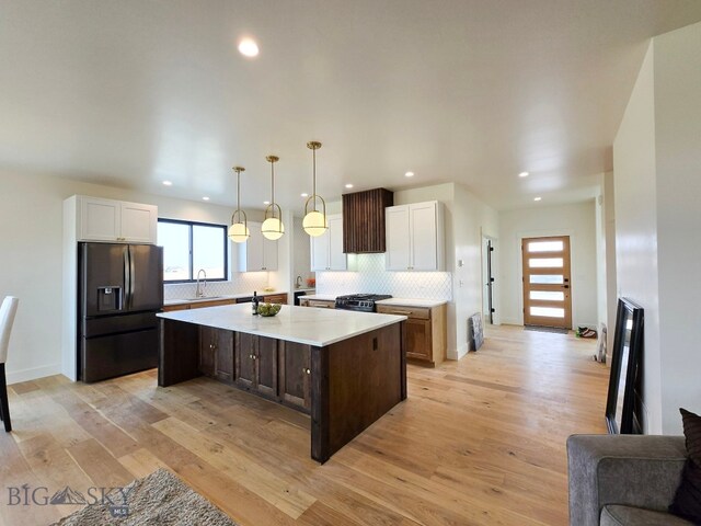 kitchen featuring decorative light fixtures, light wood-type flooring, fridge with ice dispenser, white cabinetry, and a kitchen island