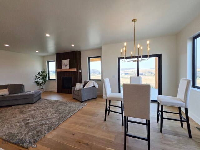 dining room featuring a chandelier, a wealth of natural light, a fireplace, and light hardwood / wood-style floors