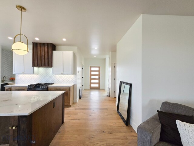 kitchen featuring hanging light fixtures, black range with gas cooktop, light wood-type flooring, and white cabinetry