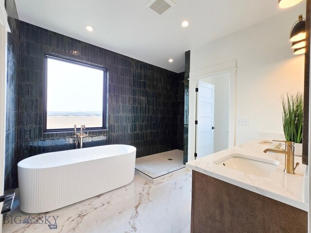 bathroom with shower with separate bathtub, vanity, and tile walls