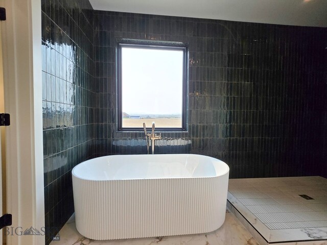 bathroom featuring tile walls, a washtub, and plenty of natural light