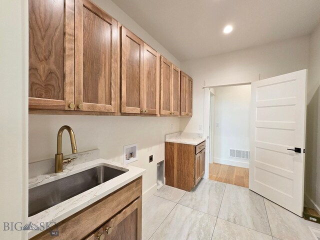 clothes washing area with hookup for a washing machine, cabinets, sink, electric dryer hookup, and light wood-type flooring