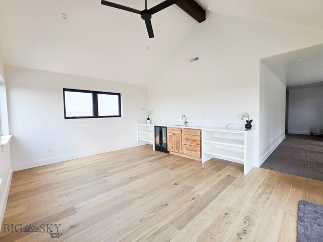 unfurnished living room featuring light wood-type flooring, sink, wine cooler, ceiling fan, and beam ceiling