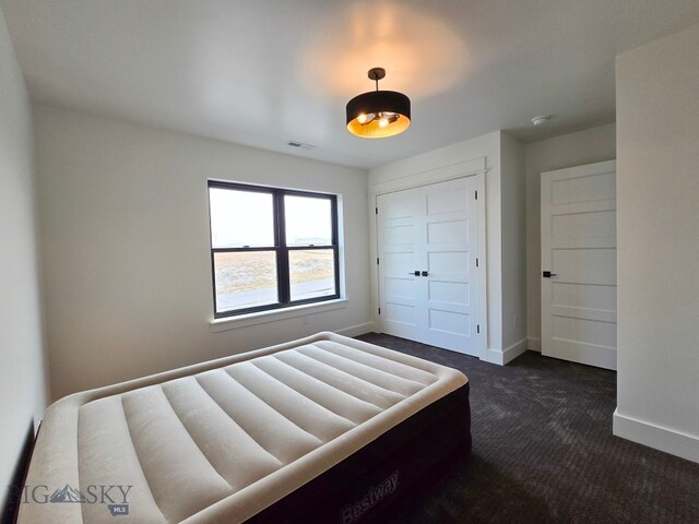 unfurnished bedroom with dark colored carpet and a closet