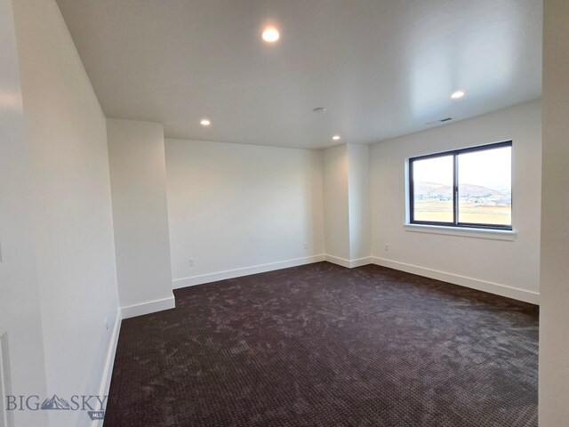 unfurnished room with dark carpet