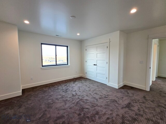 unfurnished bedroom featuring dark colored carpet and a closet