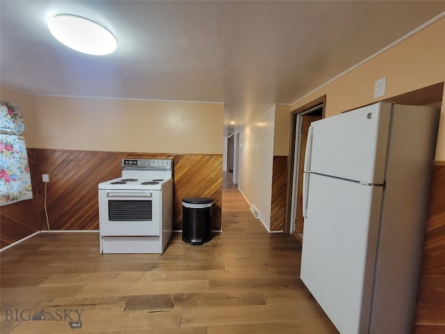 kitchen featuring hardwood / wood-style flooring, wooden walls, and white appliances