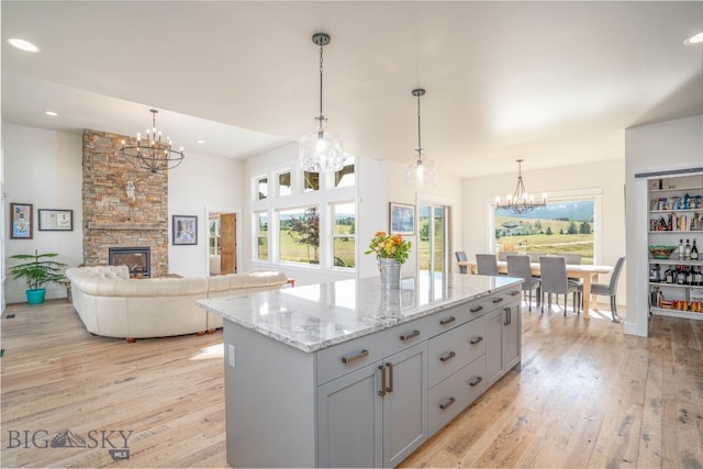 kitchen featuring pendant lighting, light wood-type flooring, an inviting chandelier, and a fireplace