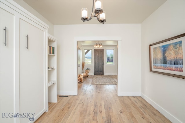 corridor with an inviting chandelier and light wood-type flooring