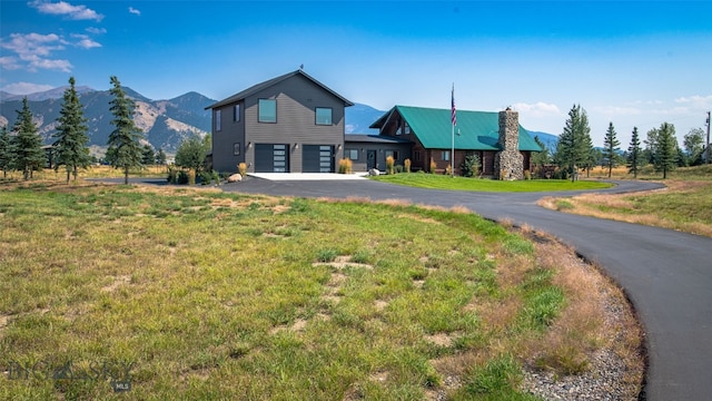 exterior space with a mountain view, a garage, and a front lawn