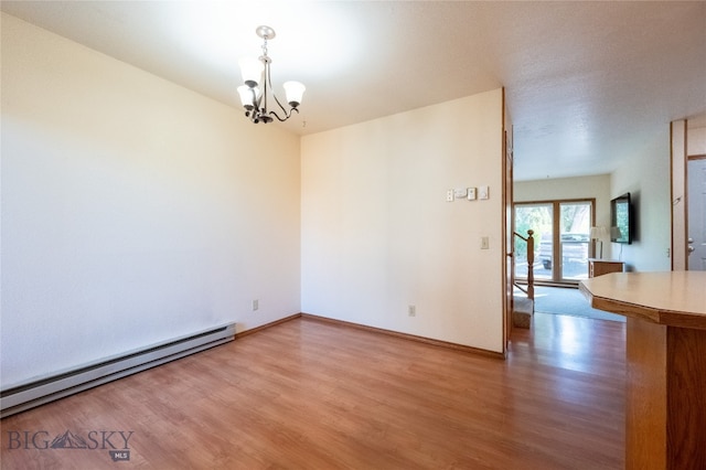 empty room with wood-type flooring, an inviting chandelier, and a baseboard heating unit