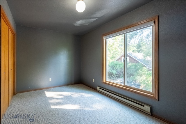 carpeted empty room featuring a baseboard radiator