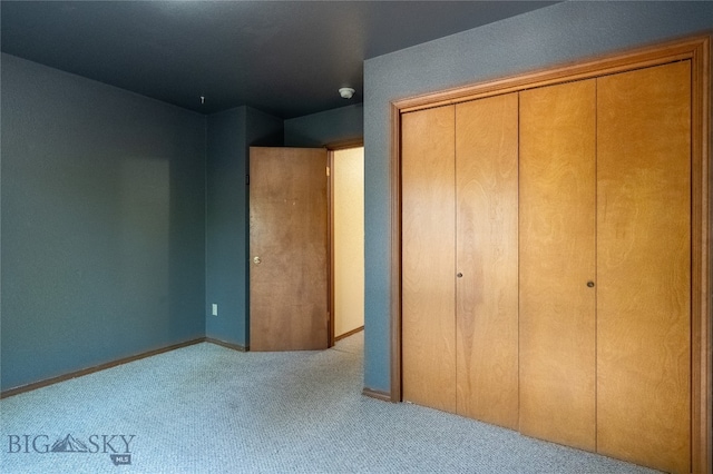 unfurnished bedroom featuring light colored carpet and a closet