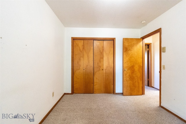 unfurnished bedroom with light carpet and a closet