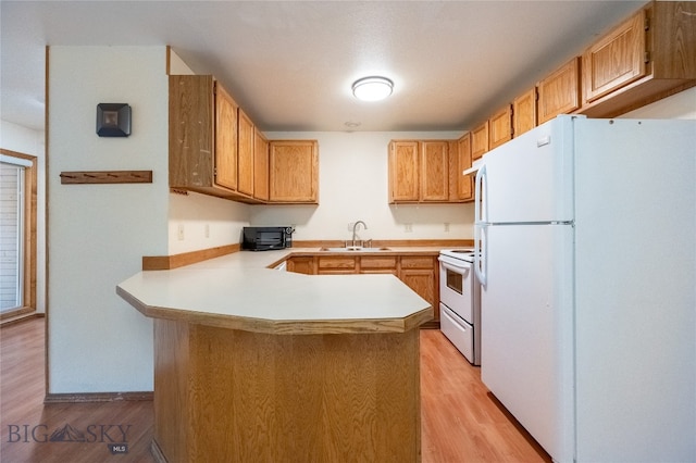 kitchen with kitchen peninsula, white appliances, light hardwood / wood-style floors, and sink