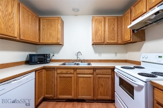 kitchen with white appliances, sink, and light hardwood / wood-style flooring