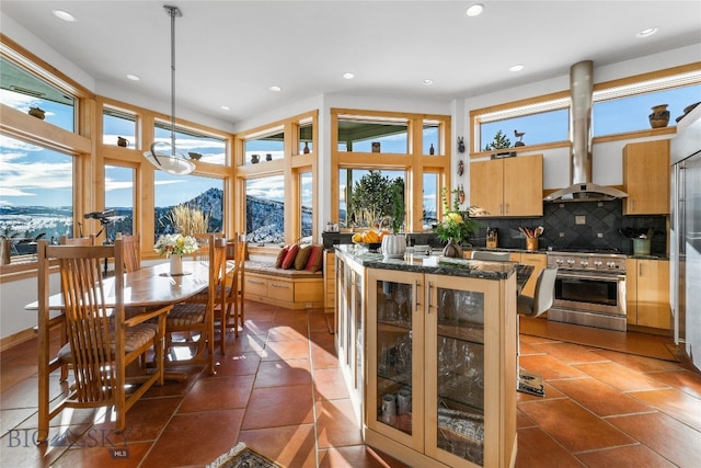 kitchen with stainless steel range, hanging light fixtures, a healthy amount of sunlight, and extractor fan