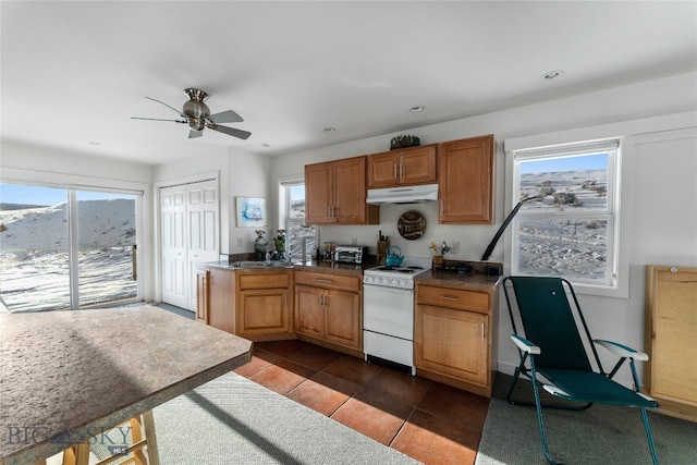 kitchen featuring white range, sink, ceiling fan, and dark tile patterned flooring