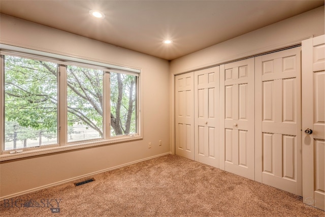 unfurnished bedroom with a closet, carpet, and multiple windows