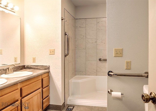 bathroom with a tile shower, tile patterned flooring, and vanity