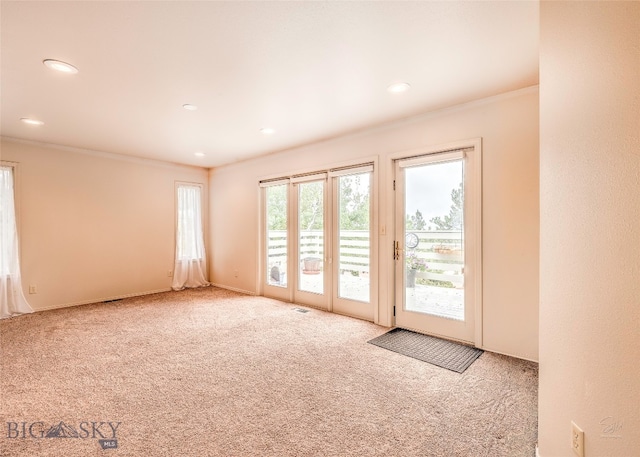 entryway with crown molding and light carpet