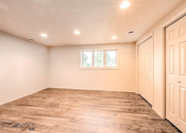 unfurnished bedroom with light hardwood / wood-style flooring and two closets