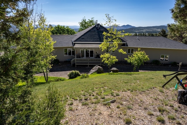 back of house with a deck with mountain view and a yard