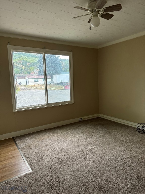 carpeted spare room featuring ornamental molding, a wealth of natural light, and ceiling fan