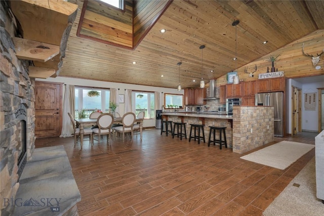 310 Highpark Dr, Anaconda, MT 59711 - kitchen with stainless steel fridge with ice dispenser, wall chimney range hood, high vaulted ceiling, wood ceiling, and brown cabinetry