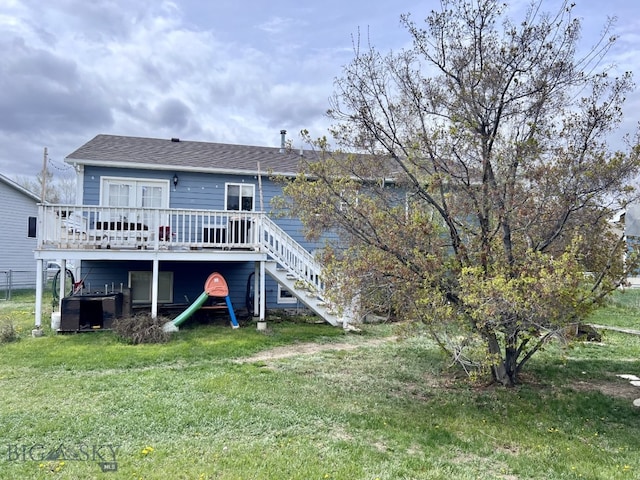 rear view of house with a wooden deck and a lawn