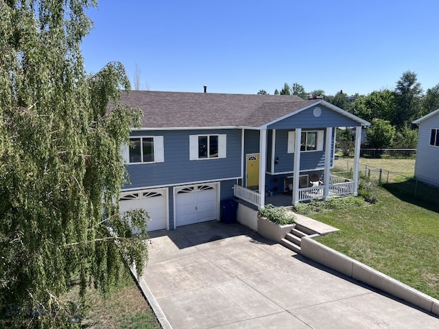 raised ranch featuring a garage, a porch, and a front lawn