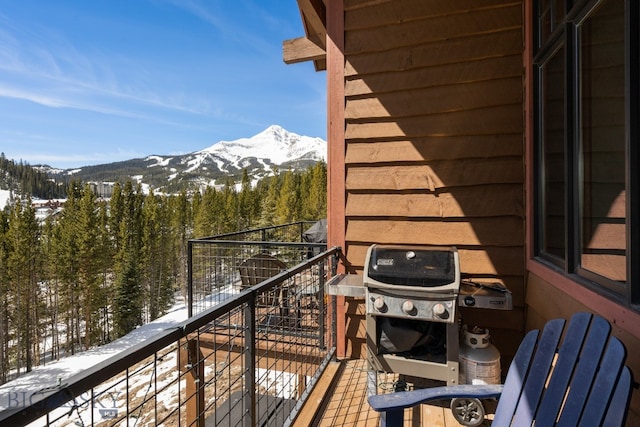 snow covered back of property featuring a mountain view and a grill