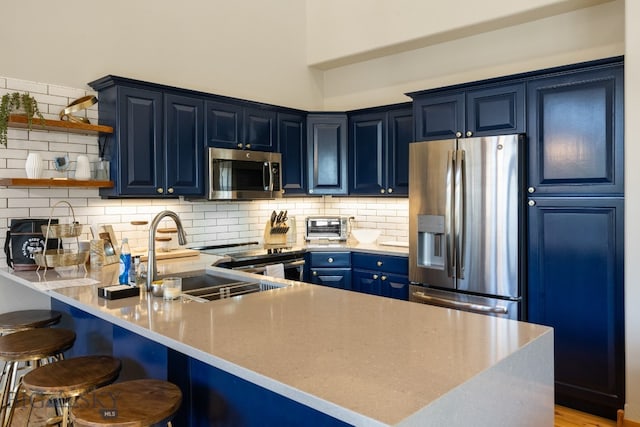 kitchen featuring sink, kitchen peninsula, decorative backsplash, appliances with stainless steel finishes, and blue cabinets