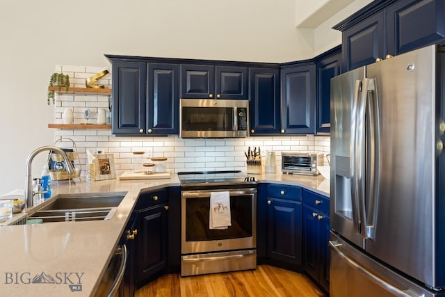 kitchen featuring tasteful backsplash, sink, light hardwood / wood-style flooring, stainless steel appliances, and blue cabinets