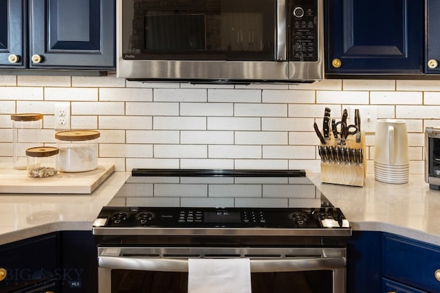 kitchen with blue cabinetry, appliances with stainless steel finishes, and backsplash